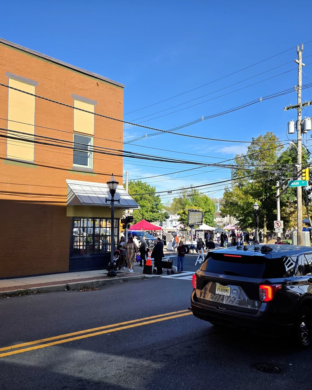 El centro de Hightstown durante el Festival de la Cosecha, con asistentes, carpas y el letrero de Main Street visible