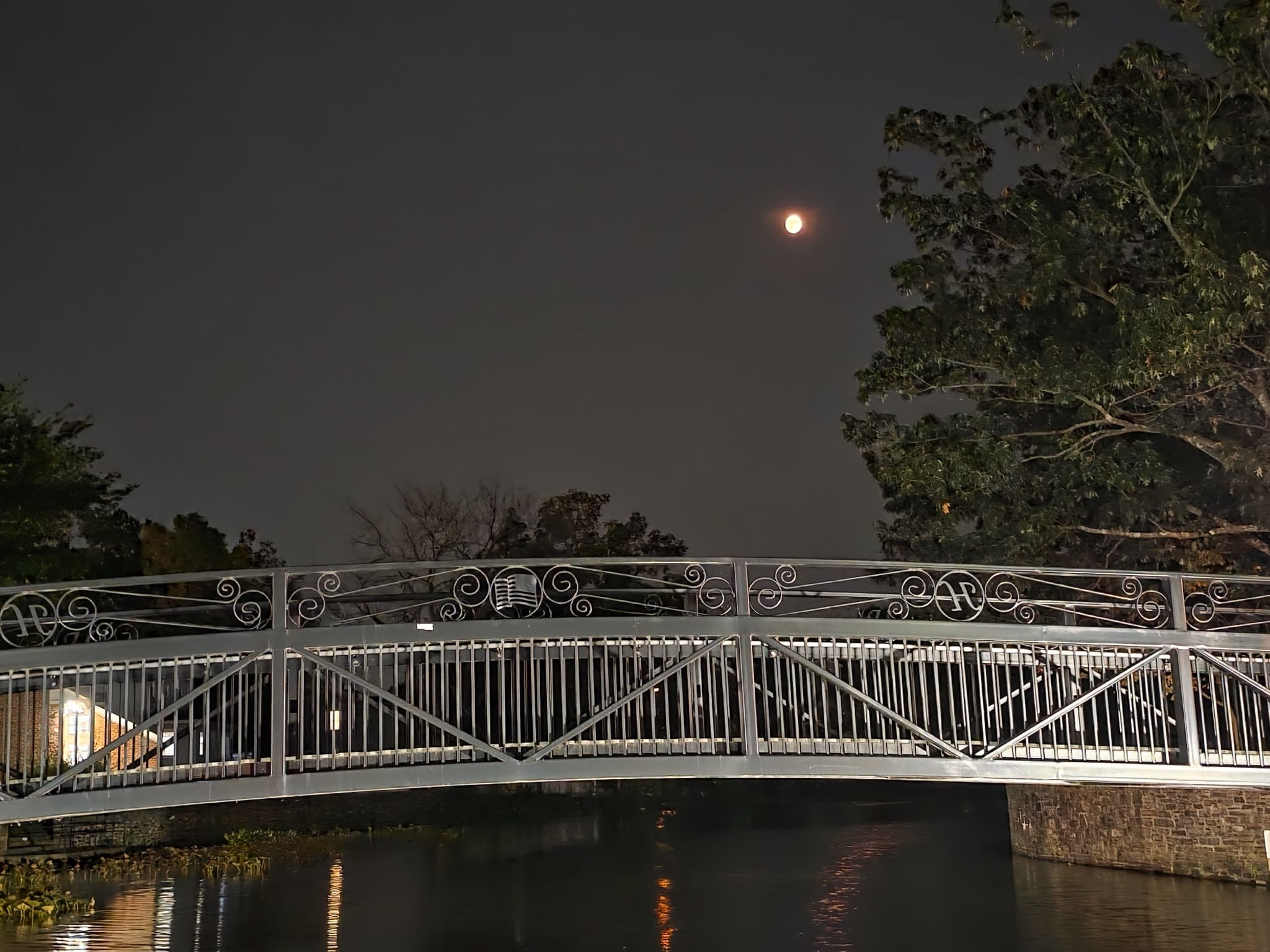 Moon above an illuminated bridge over the water