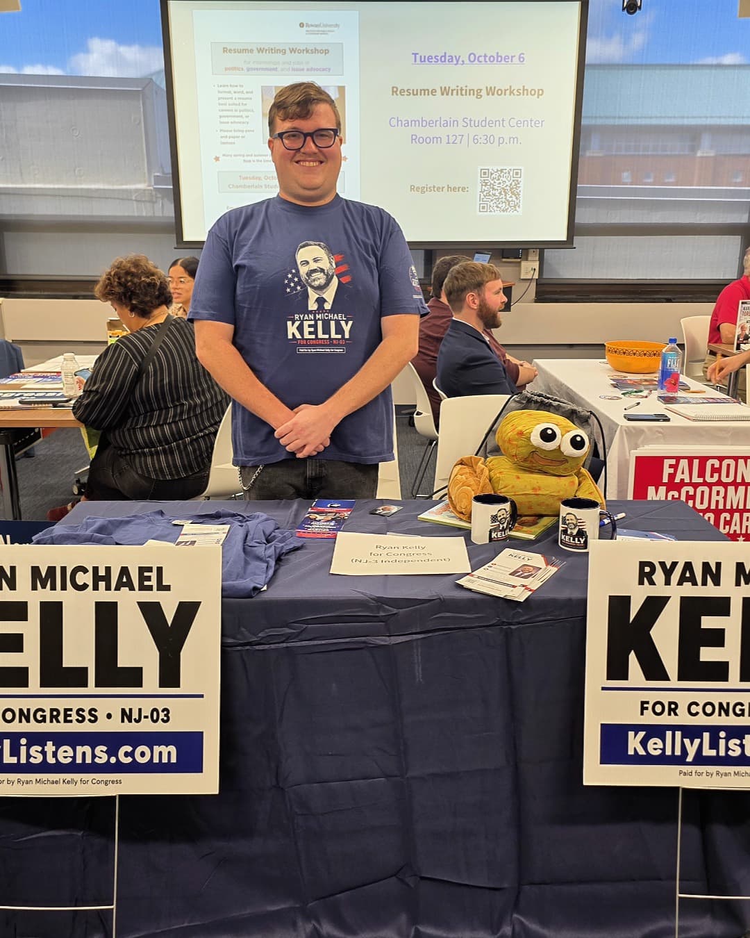 El estudiante de Rowan University, Ian, está detrás de la mesa de Kelly for Congress con una camiseta de la campaña durante la Feria de Voluntariado de Campañas Políticas de RIPPAC