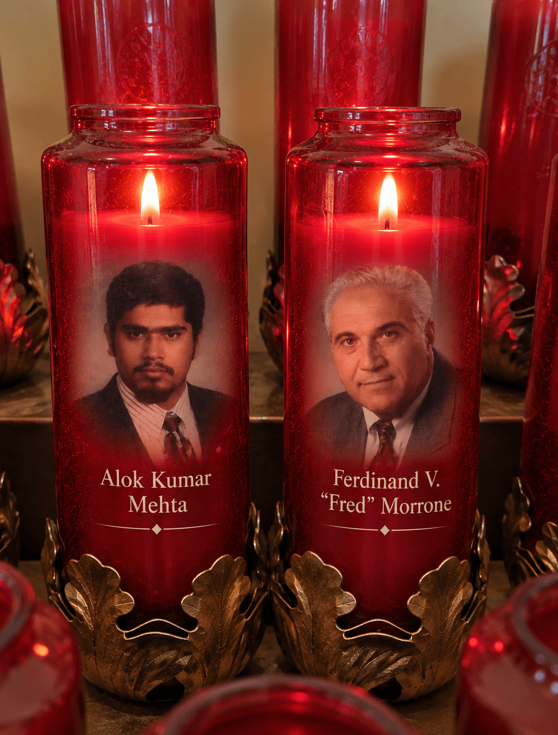 Memorial tribute image with two illuminated red candles honoring Alok Kumar Mehta and Ferdinand V. “Fred” Morrone, with their portraits and names