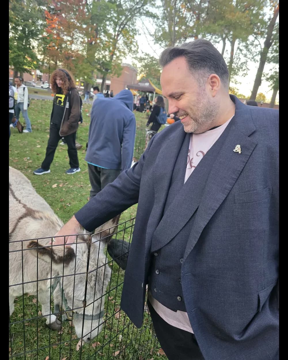 Ryan Michael Kelly sonríe mientras acaricia a un burro en el festival.